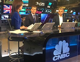 Damian takes New York 6 Three newsreaders seated at the CNBC news desk.