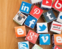The Signature Link to Social Success 2 Many cardboard cubes grouped together on a wooden surface, each with a different social media platform logo printed onto it.
