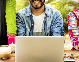 7 ways a personalised demo ensures you choose the right email signature solution 9 A close-up of a man sitting behind a laptop, with people either side.