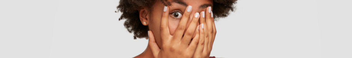 Email Signature Solutions for scary business challenges A close-up of a woman covering her face with her hands, with one eye visible.