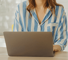 Professionalism in PJ’s. Musings from a remote-working Rocketseed newbie 12 A woman sits behind a laptop in a striped blue shirt.