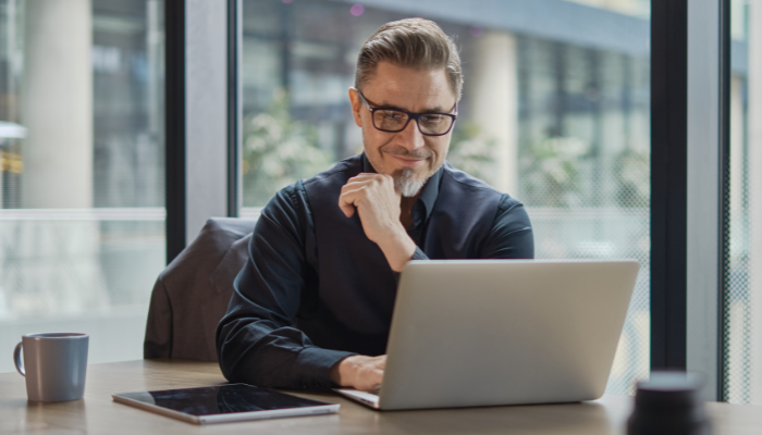 How American Corporations Are Saving Time Managing Email Signatures at Scale 7 A professional man working on a laptop in modern office setting