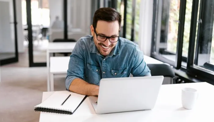 How to Achieve MSP Advantage: Add Email Signature Management as a Service 13 A smiling man sitting behind a desk working on his laptop
