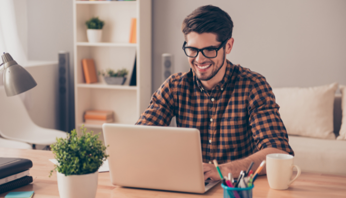 The Game-Changer SaaS Partner Program for MSPs 6 Cheerful young man in glasses typing on laptop in a casual setting